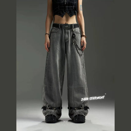 A pair of wide-leg denim jeans with a belt design at the bottom, featuring a mix of blue and green shades, and embellished with metal details and a chain.