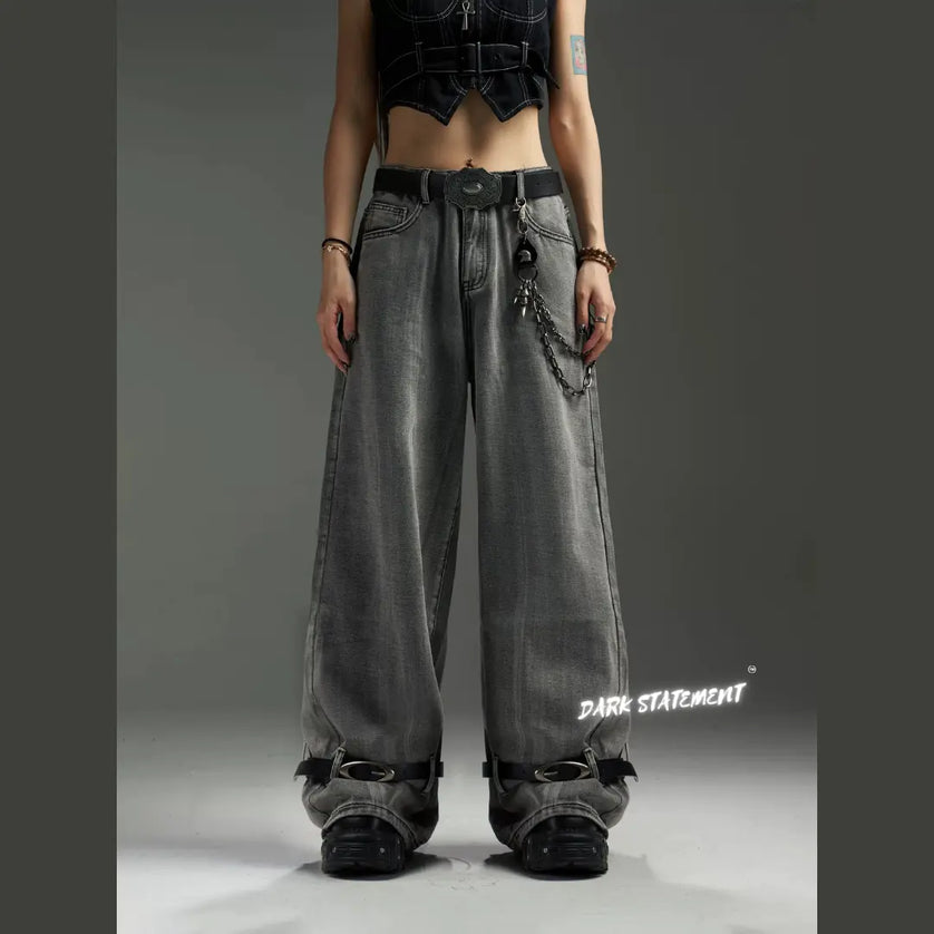 A pair of wide-leg denim jeans with a belt design at the bottom, featuring a mix of blue and green shades, and embellished with metal details and a chain.