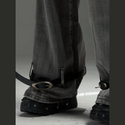 A pair of wide-leg denim jeans with a belt design at the bottom, featuring a mix of blue and green shades, and embellished with metal details and a chain.