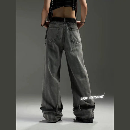 A pair of wide-leg denim jeans with a belt design at the bottom, featuring a mix of blue and green shades, and embellished with metal details and a chain.
