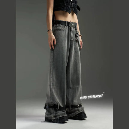 A pair of wide-leg denim jeans with a belt design at the bottom, featuring a mix of blue and green shades, and embellished with metal details and a chain.