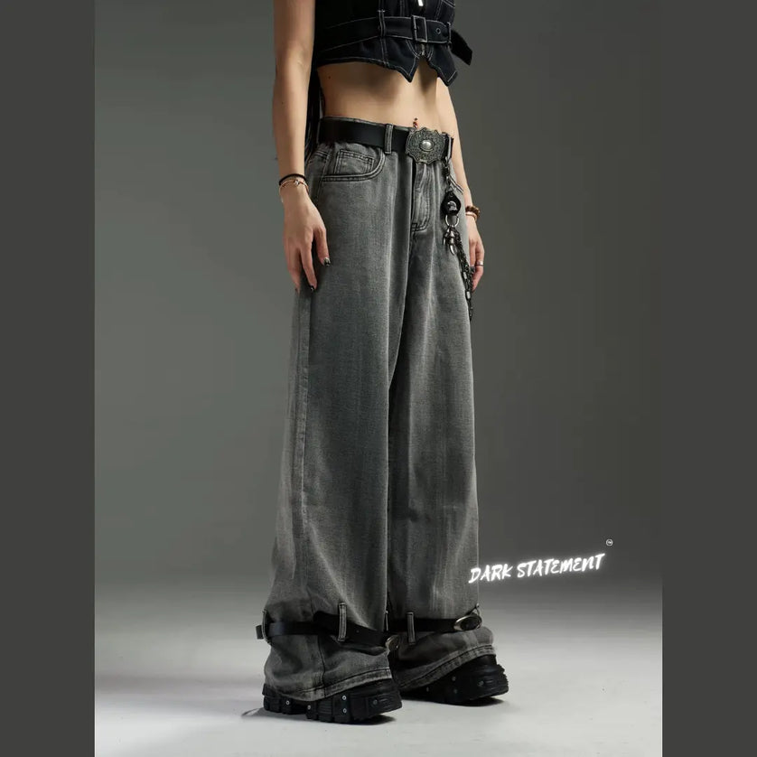 A pair of wide-leg denim jeans with a belt design at the bottom, featuring a mix of blue and green shades, and embellished with metal details and a chain.